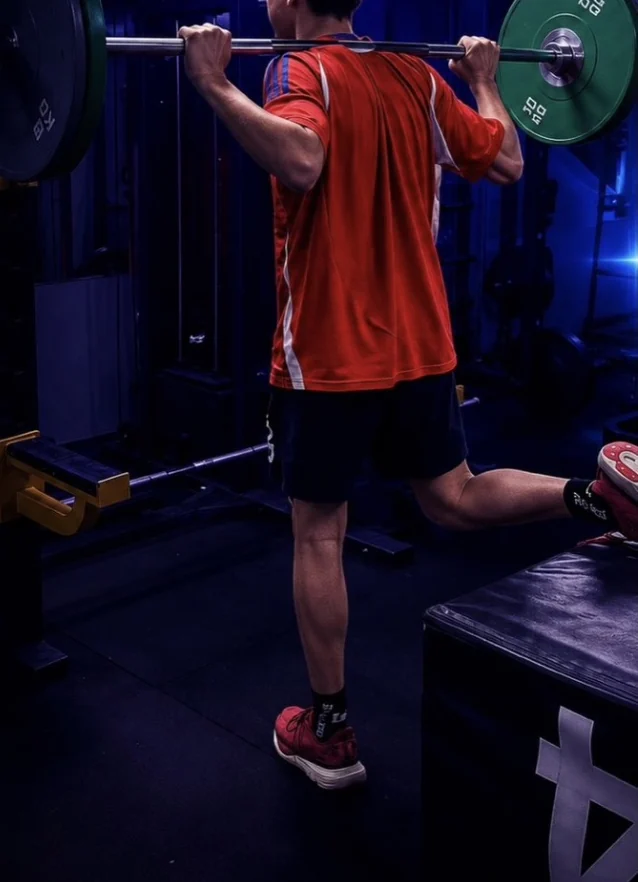 Deportista entrenando con barra, de espaldas